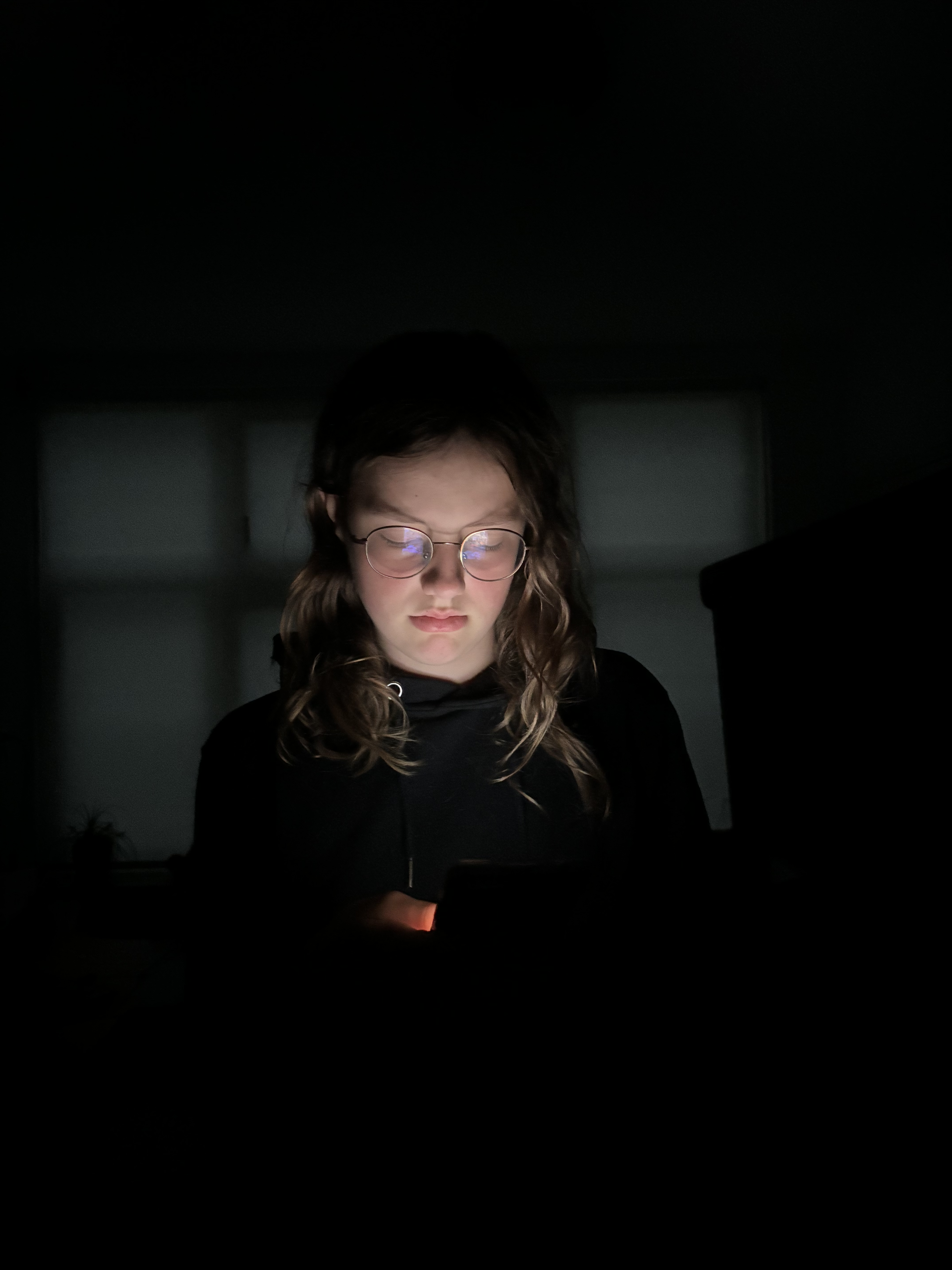 Een foto genomen van rechtvoor van een meisje die de telefoon vasthoud en verdrietig kijkt