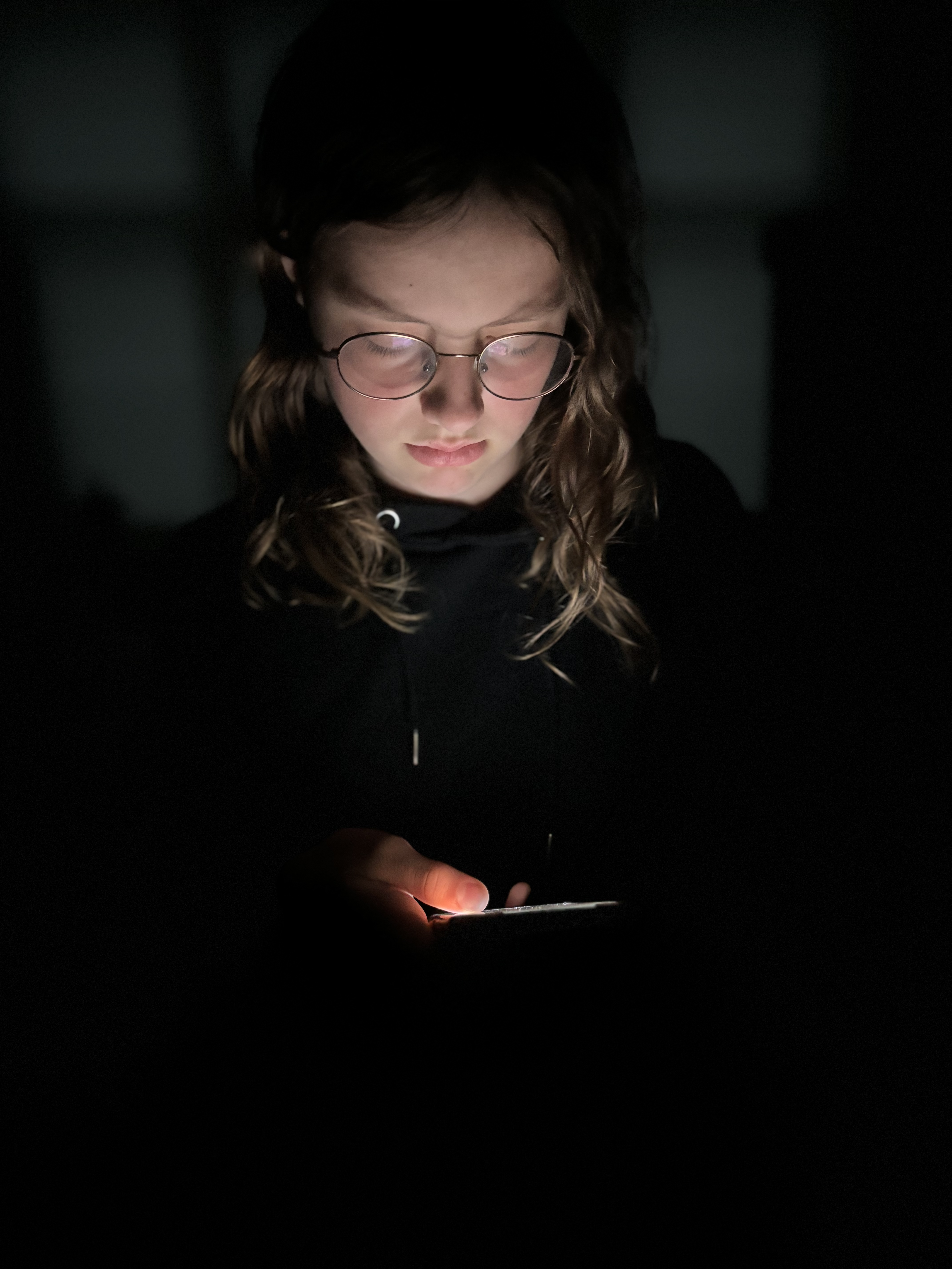 Een foto genomen van boven van een meisje die de telefoon vasthoud en verdrietig kijkt